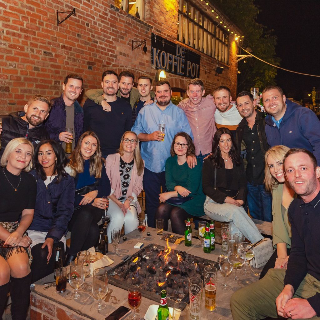 Group of people enjoying a drink outside by a firepit at Left Bank Village